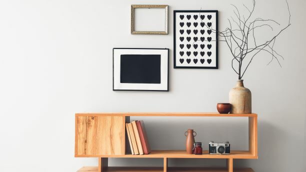 A wooden bench filled with books and decoration. Stylish art pieces hanging on the wall, enhancing the ambiance of the home.